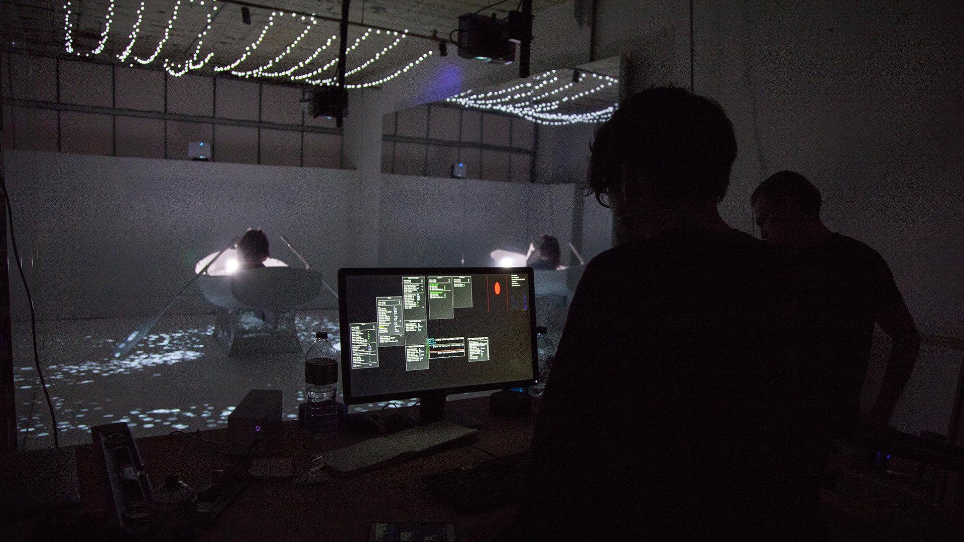 behind the scenes of interactive installation, dark room with projections and a rowboat