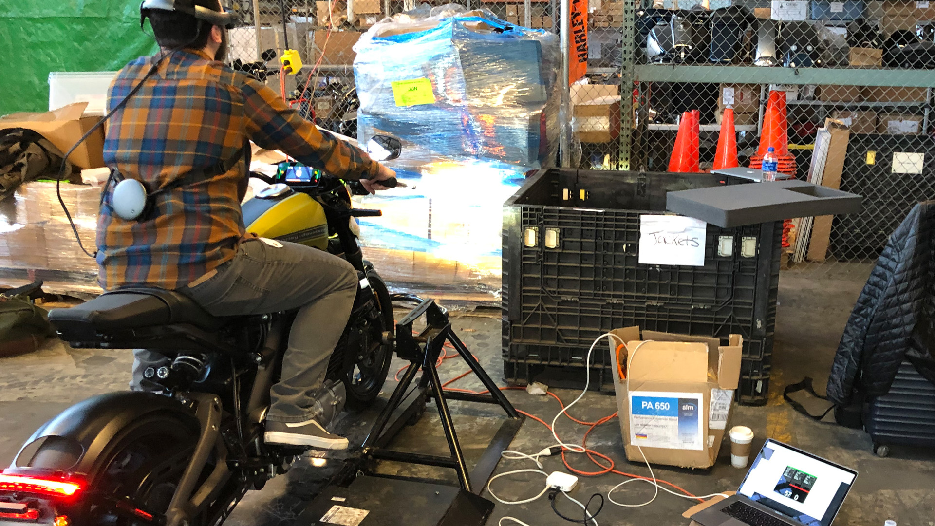 behind the scenes of interactive installation, in a warehouse, man riding harley electric motorcycle while wearing mixed reality headset
