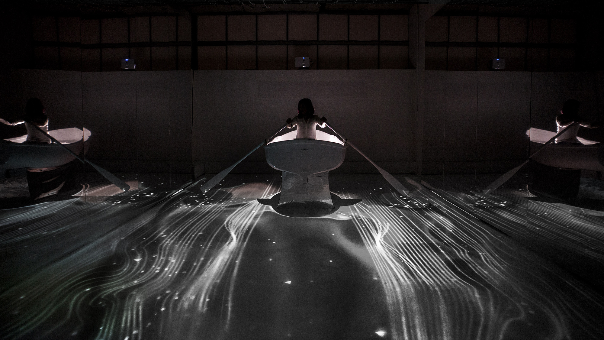 image of woman in rowboat interacting with digital stars and water projections all around her