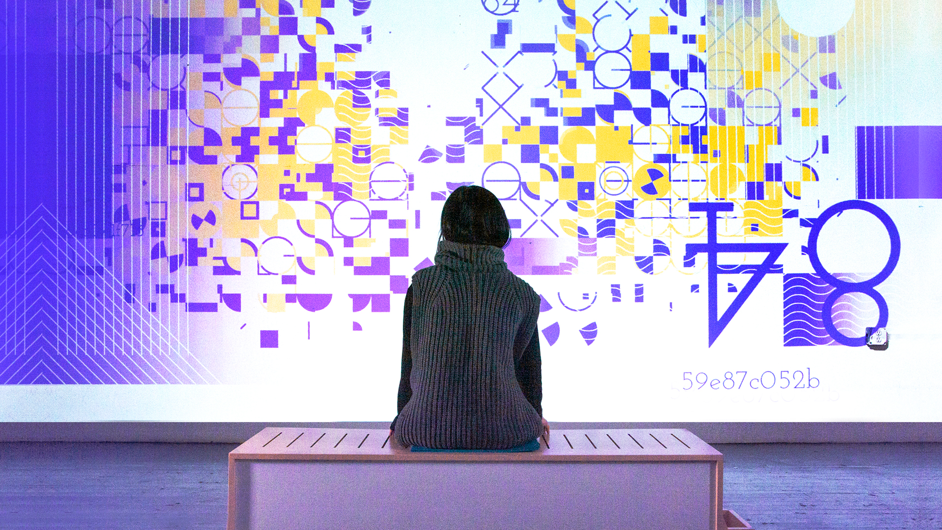 a girl sits on butchain bench and watches her unqiue blockchain art generate on the screen in front of her