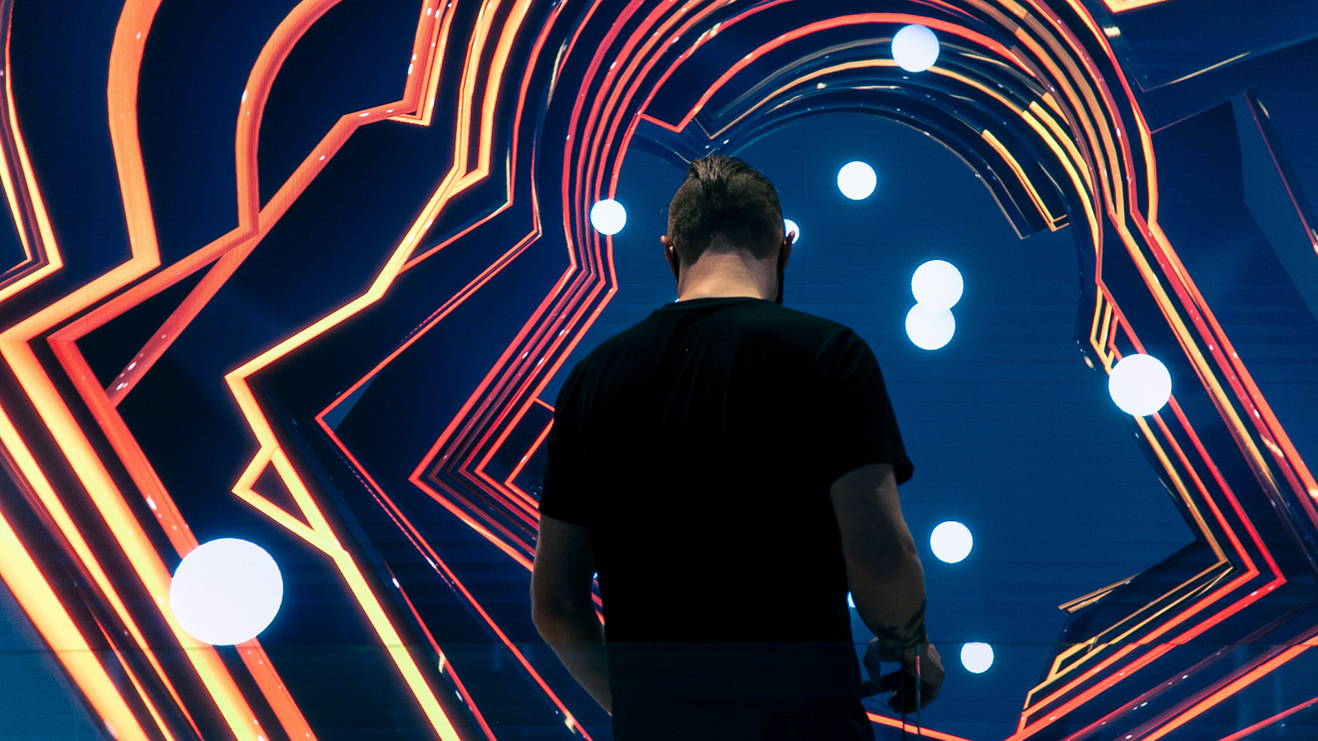 A close up of a person standing in front of a large screen with his back to the camera. The screen displays the night version of the interactive data visualization called Day by Red Paper Heart.