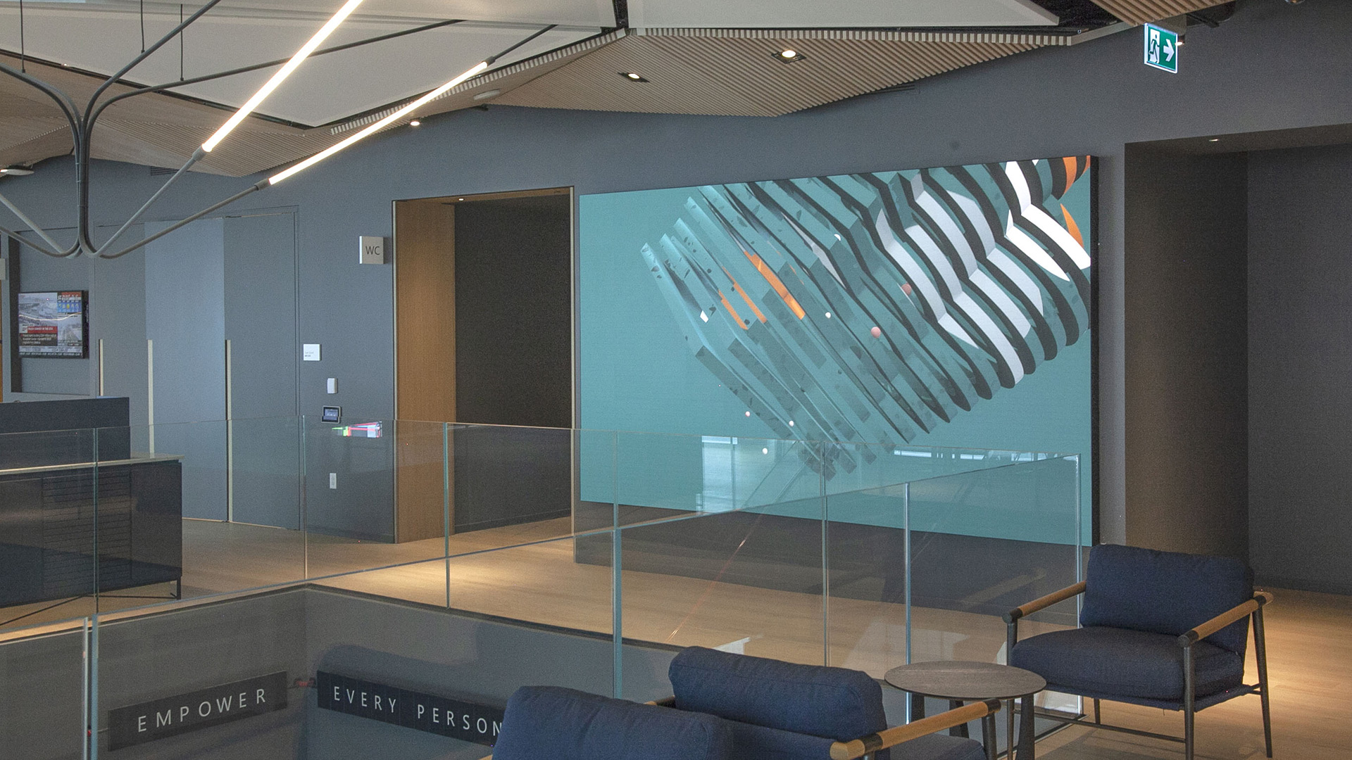 A stylish new lobby with a large screen. The screen displays the digital sculpture called Day. The sculpture is made up of rings. Each ring is a representation of the consumption data of the building.