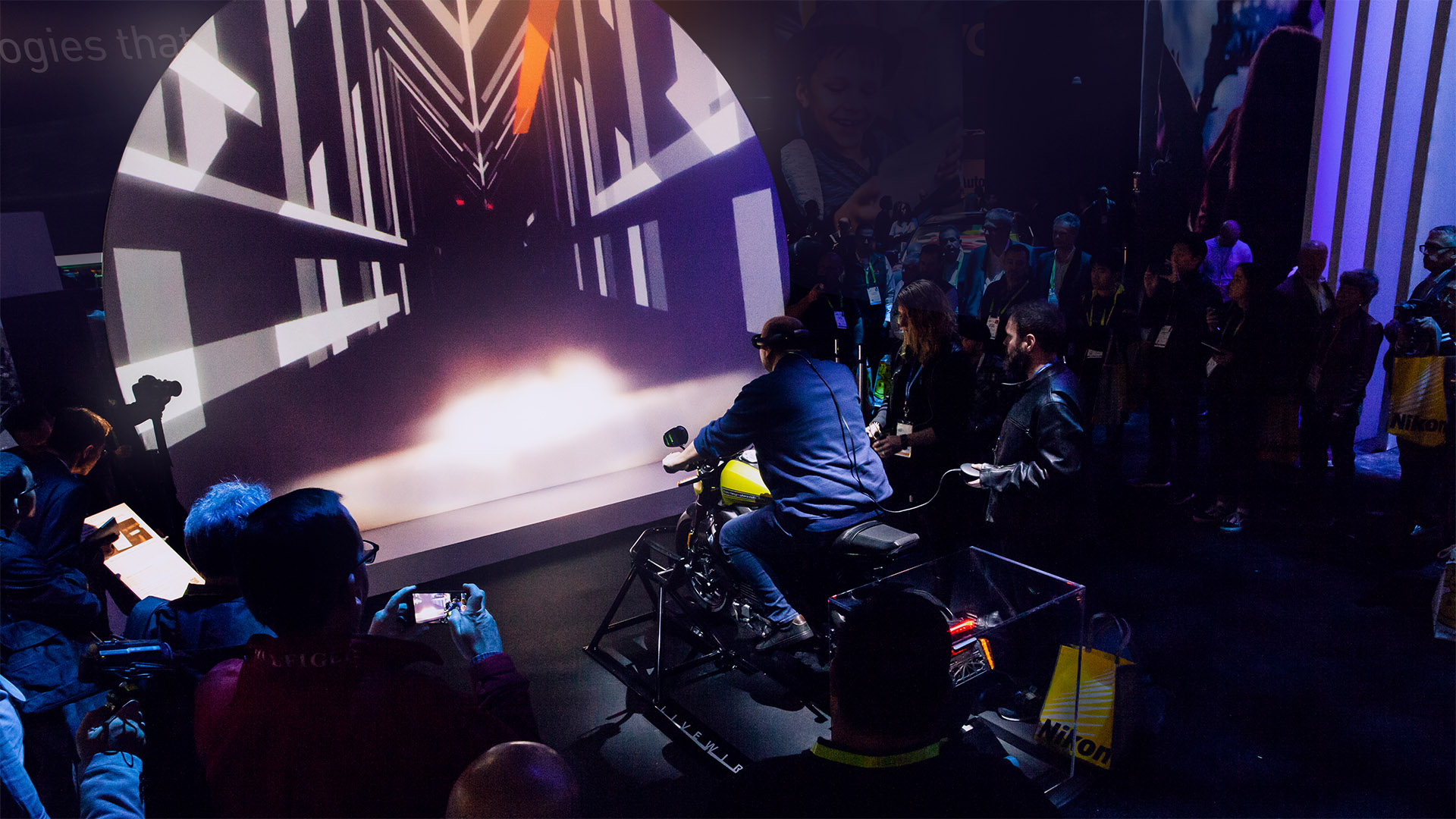 An enthralled crowd watches a person immerse themselves in a VR experience on Harley Davidson's LiveWire electric motorcycle, embodying the thrilling intersection of innovation and adventure.