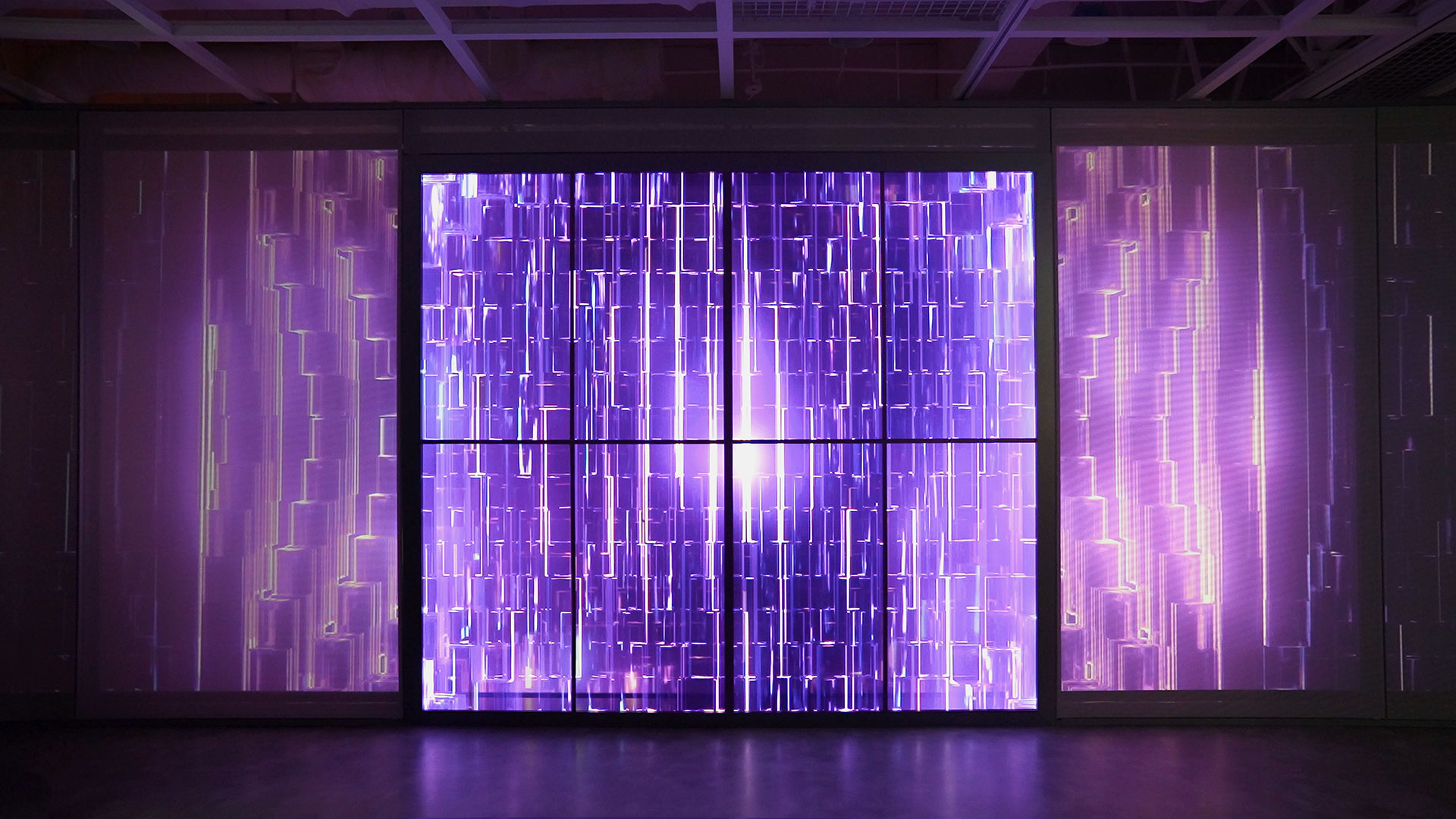 a dark room with large projection wall, purple crystal refractive graphics on screen