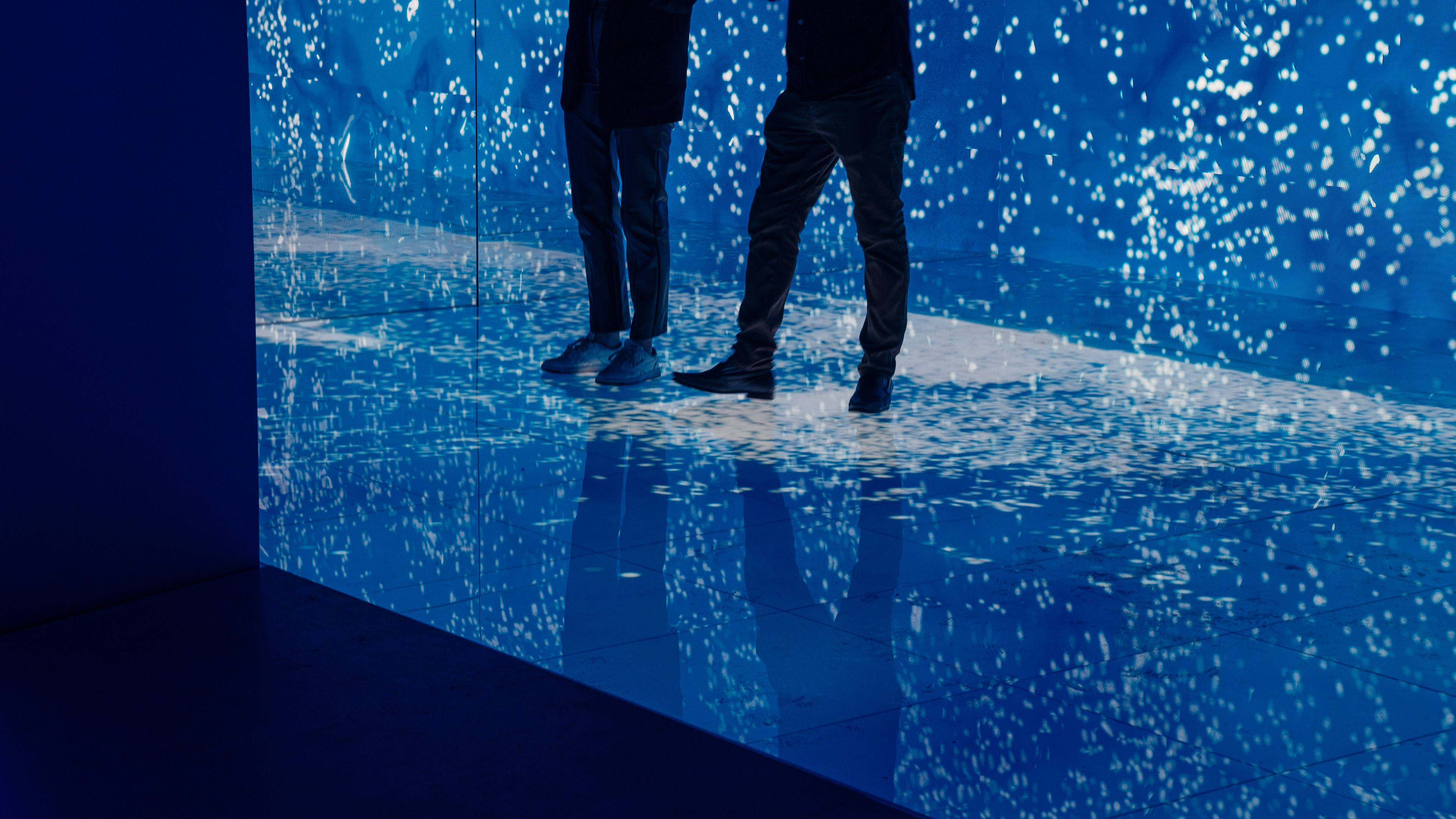 Two people standing on an led floor with dynamic water graphics