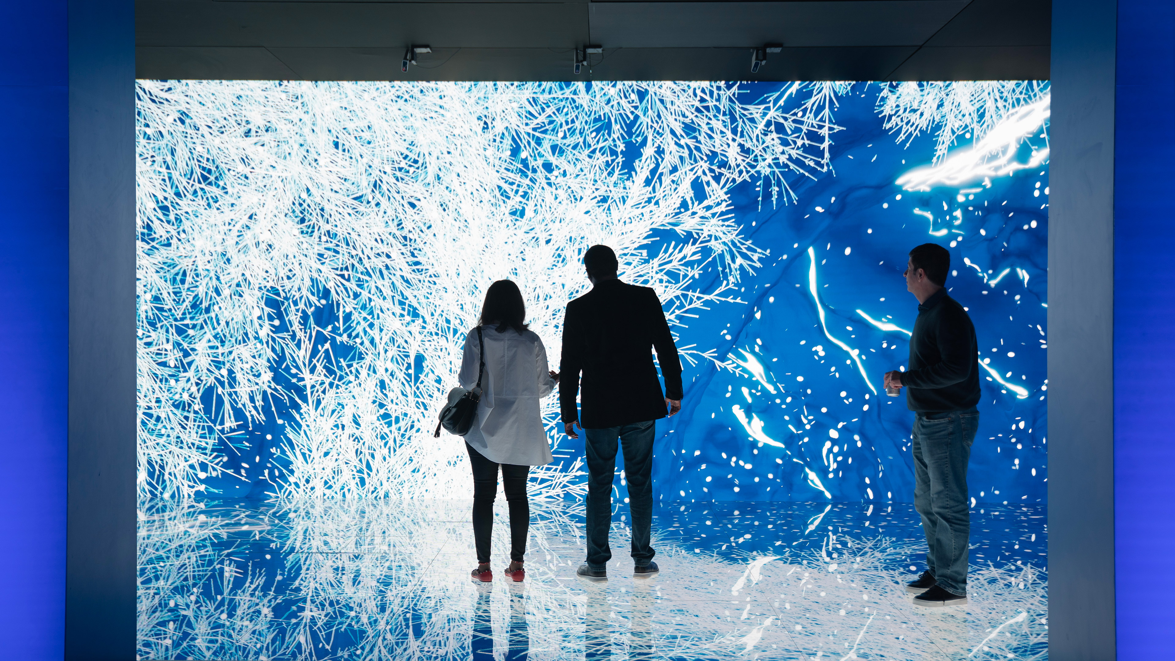 Three people standing in front of a large led wall and led floor. frost crystals are dynamically filling the screens