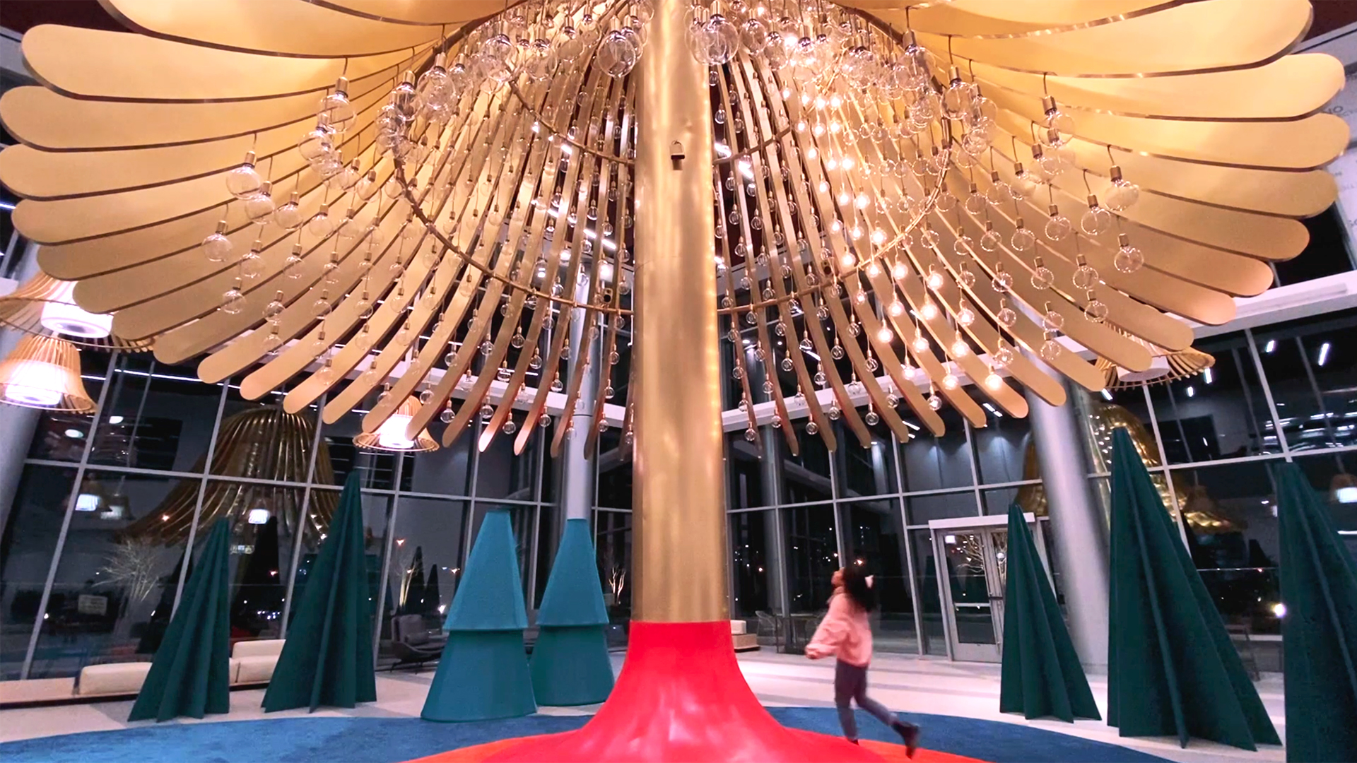 Girl runs underneath large central bell as motion sensors track her movements. She triggers sound and light from underneath the bell arms.