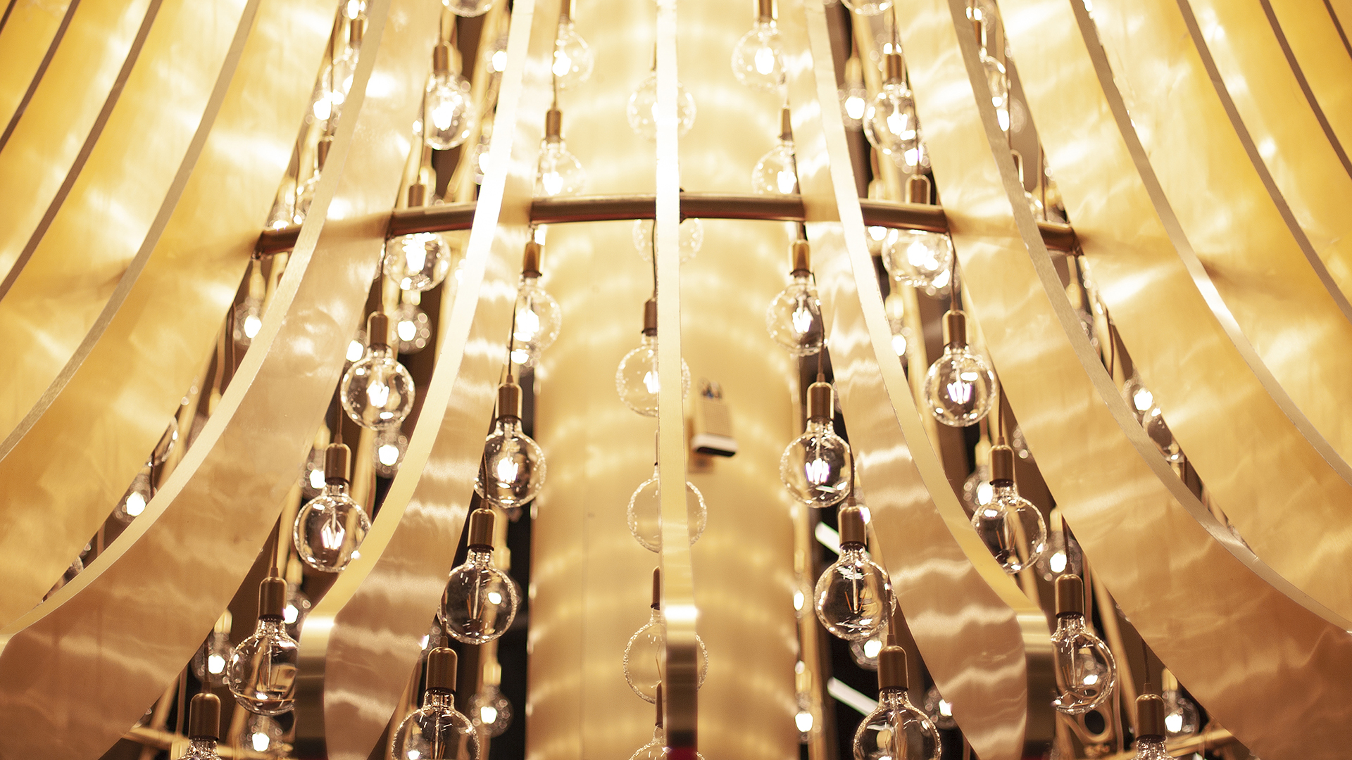 Several gold arms create a bell-like structure with addressable light bulbs hanging from each arm