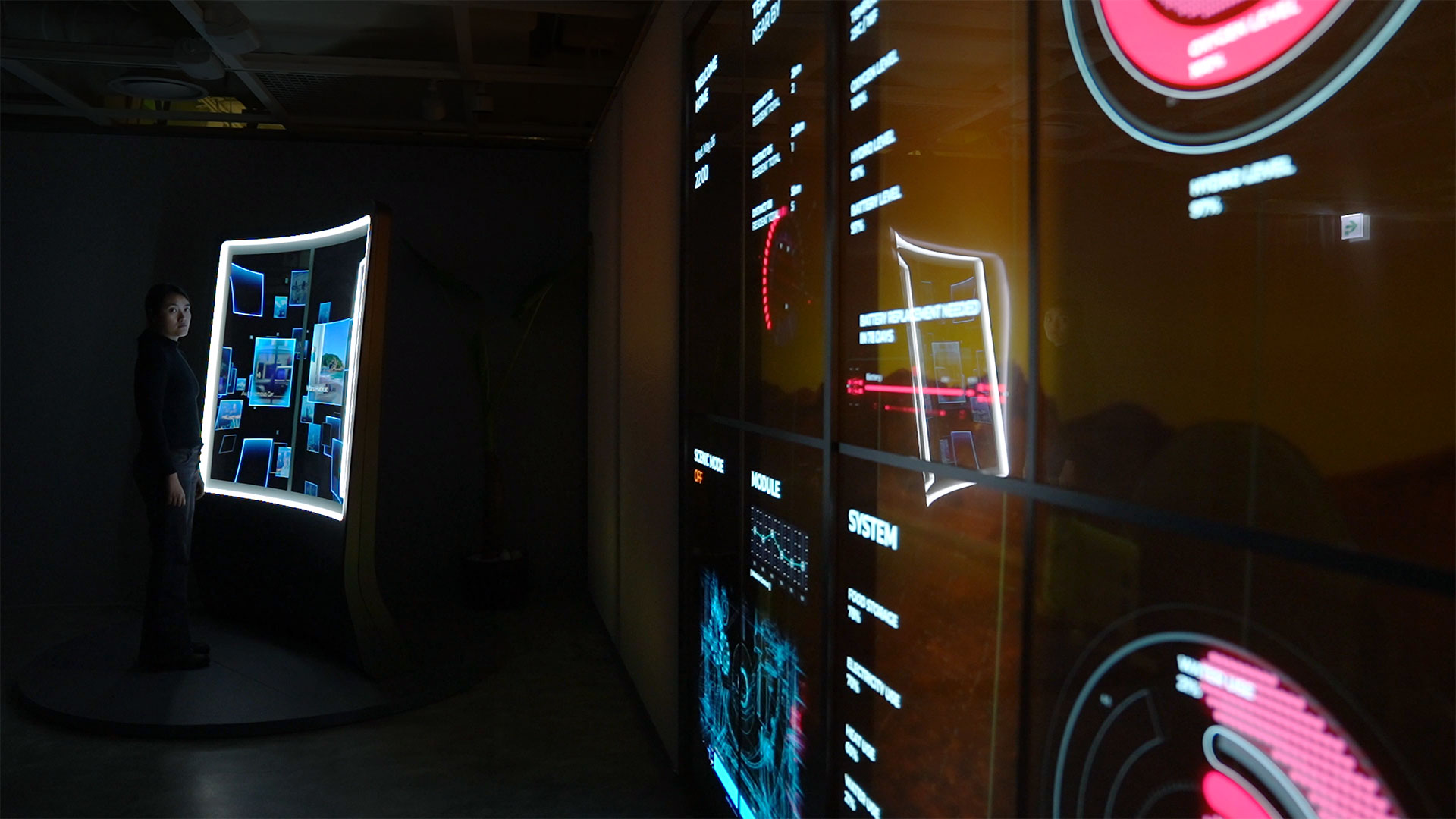 a dark room with a large interactive transparent oled screen. informational graphics are displayed on opposite wall